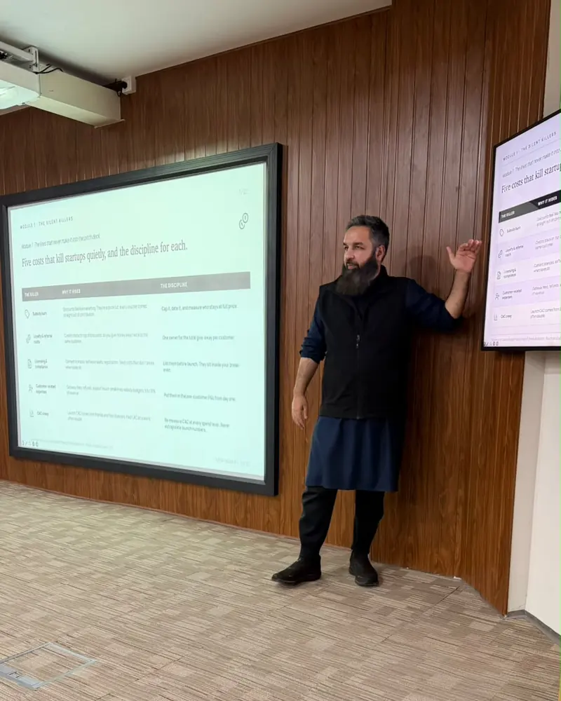 Umar Muhammad Sharif pointing to a slide on a projection screen in a wood-panelled training room